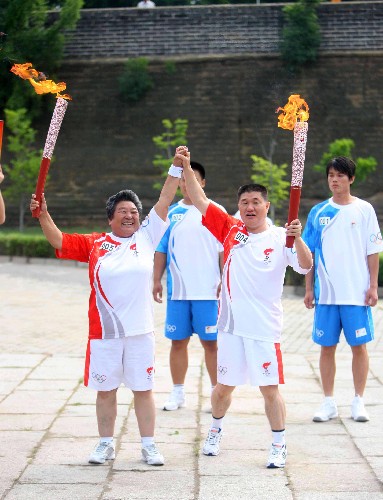 7月30日,火炬手孫剛(右)與下一棒火炬手林秀貞交接后展示火炬。當日,北京奧運圣火在河北省秦皇島市傳遞。新華社記者 邢廣利 攝